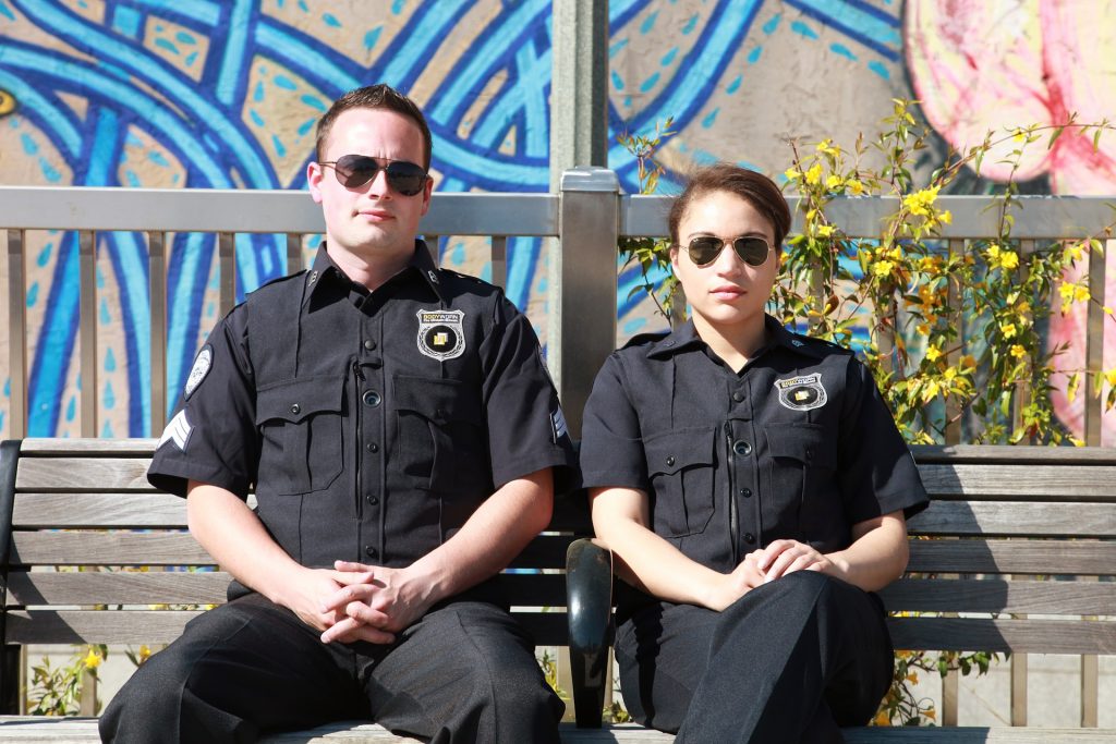 Two police officers sitting on outdoor bench wearing sunglasses